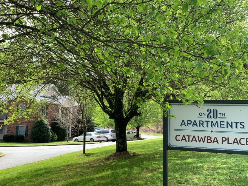 a sign that is in the grass near a tree