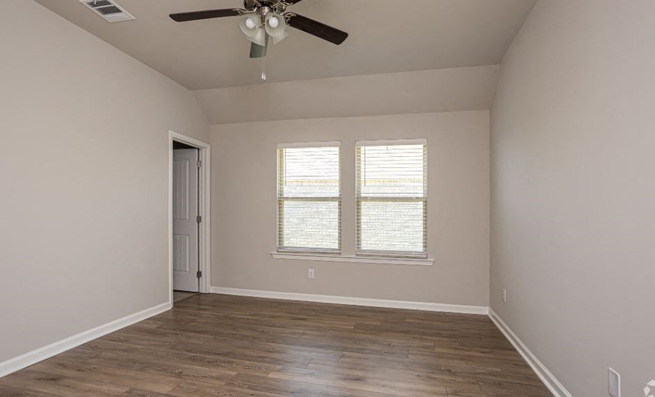 a empty room with a ceiling fan and two windows