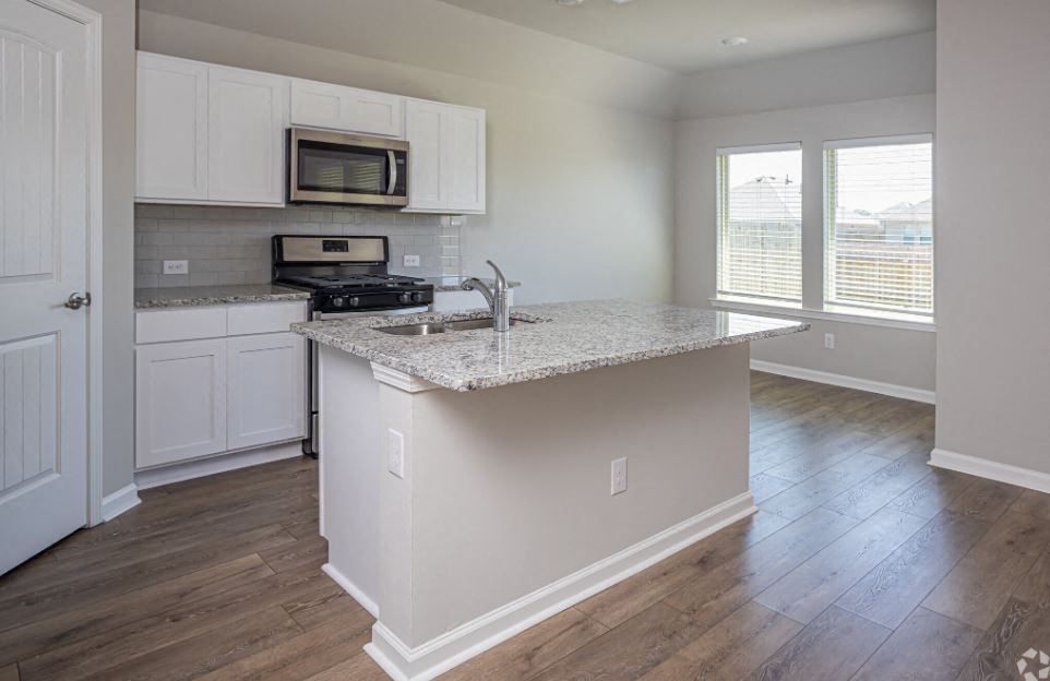 an empty kitchen with a granite counter top
