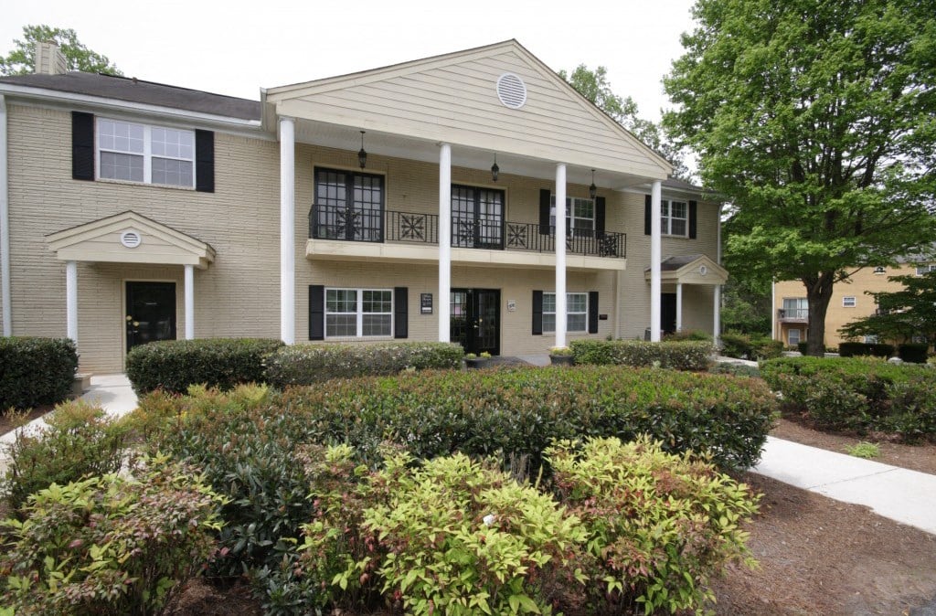 the front of a building with bushes and a sidewalk