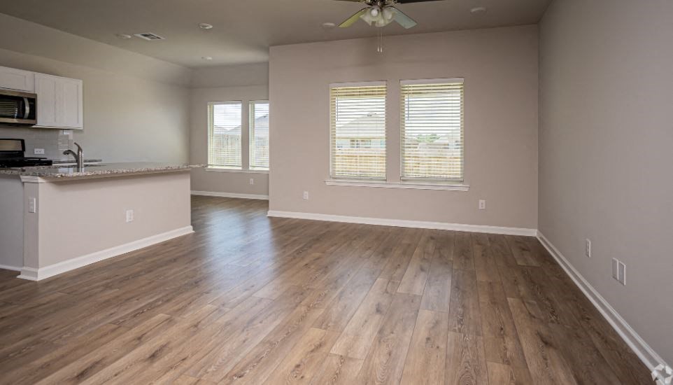 an empty living room and kitchen with wood floors