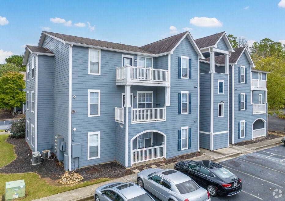 a blue apartment building with cars parked in a parking lot