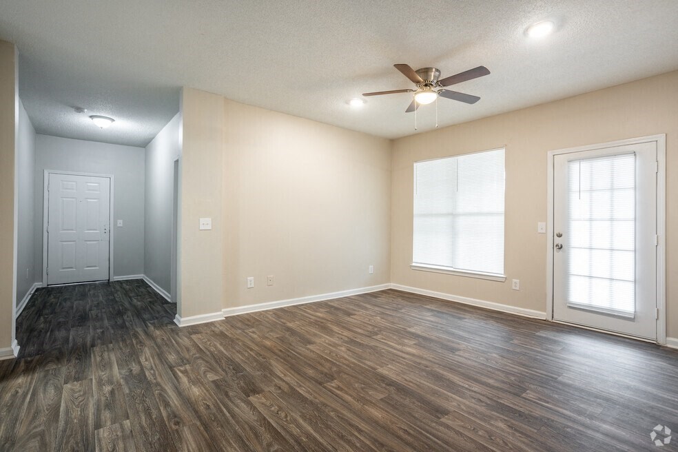 an empty living room with a ceiling fan and a window