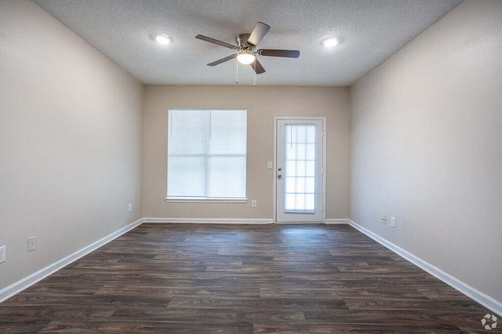 an empty living room with a ceiling fan and a window