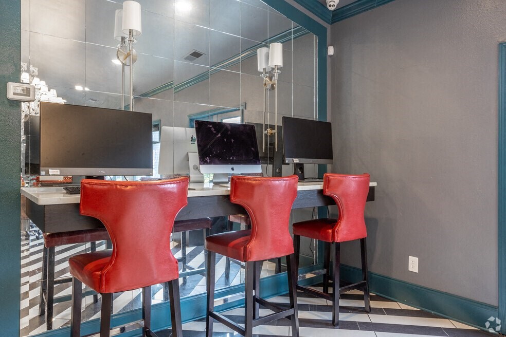 a computer desk with red chairs in front of a mirror