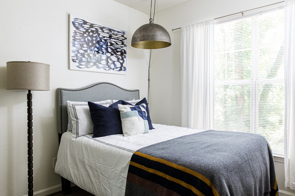 a bedroom with white walls and a bed with blue and white bedding