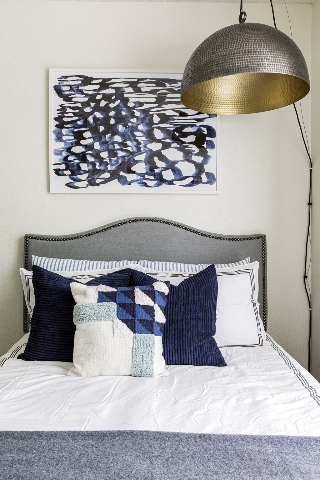 a bedroom with a large lamp and a bed with blue and white pillows