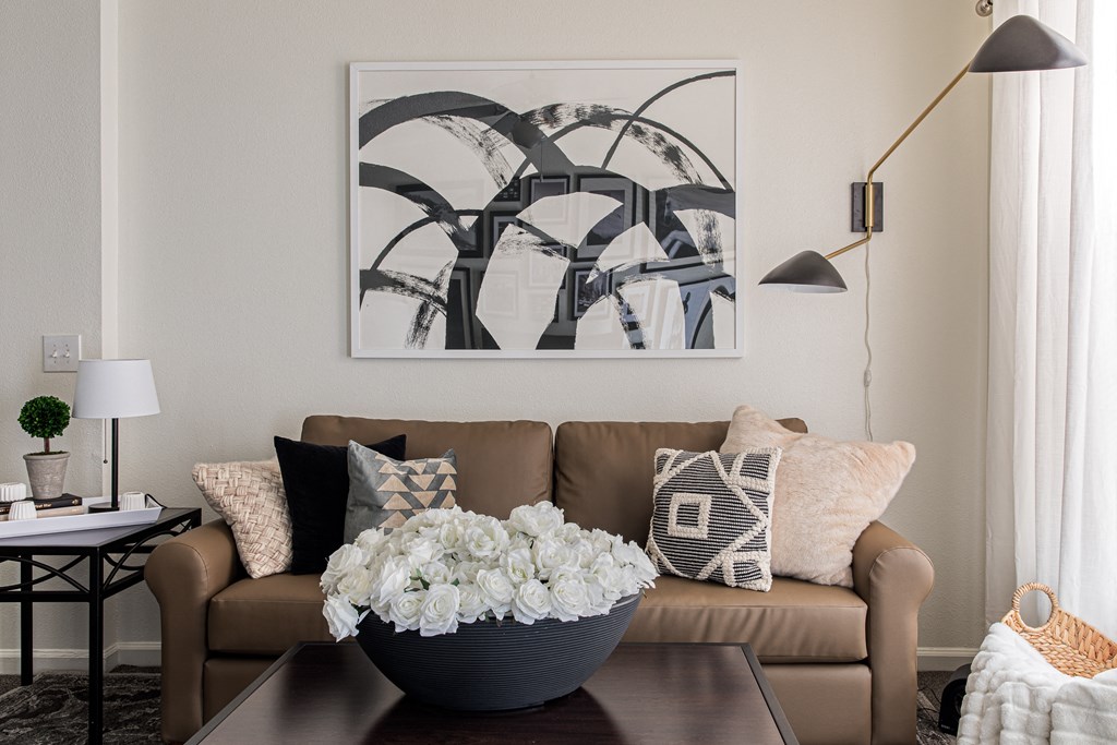 a living room with a couch and a coffee table with a vase of flowers on it