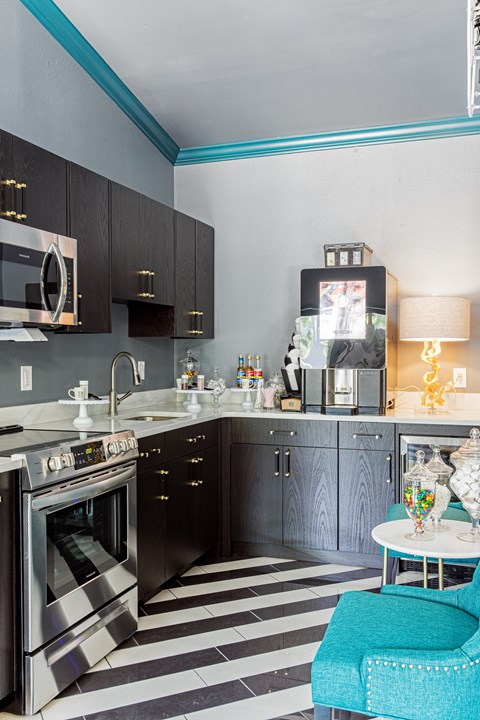 a kitchen with stainless steel appliances and black and white striped floors and a blue chair