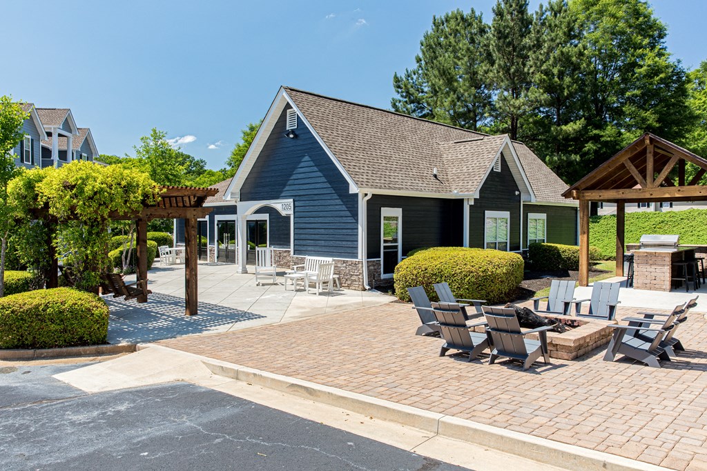 a patio with chairs and a fire pit in front of a blue building
