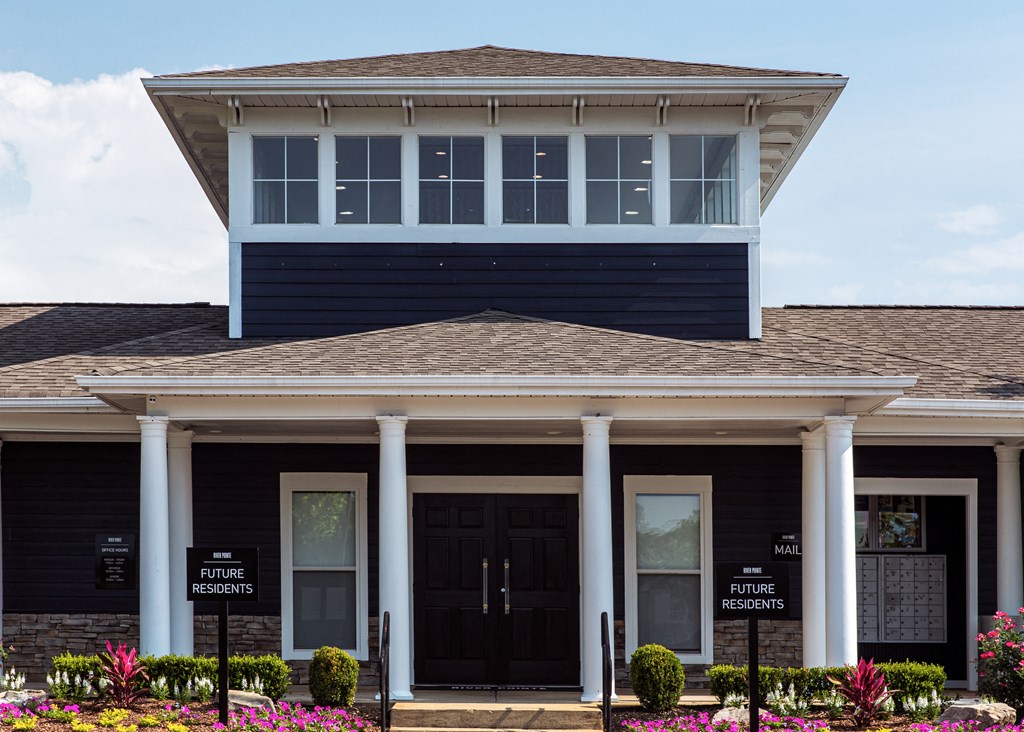 the front of a house with two black doors and two white columns