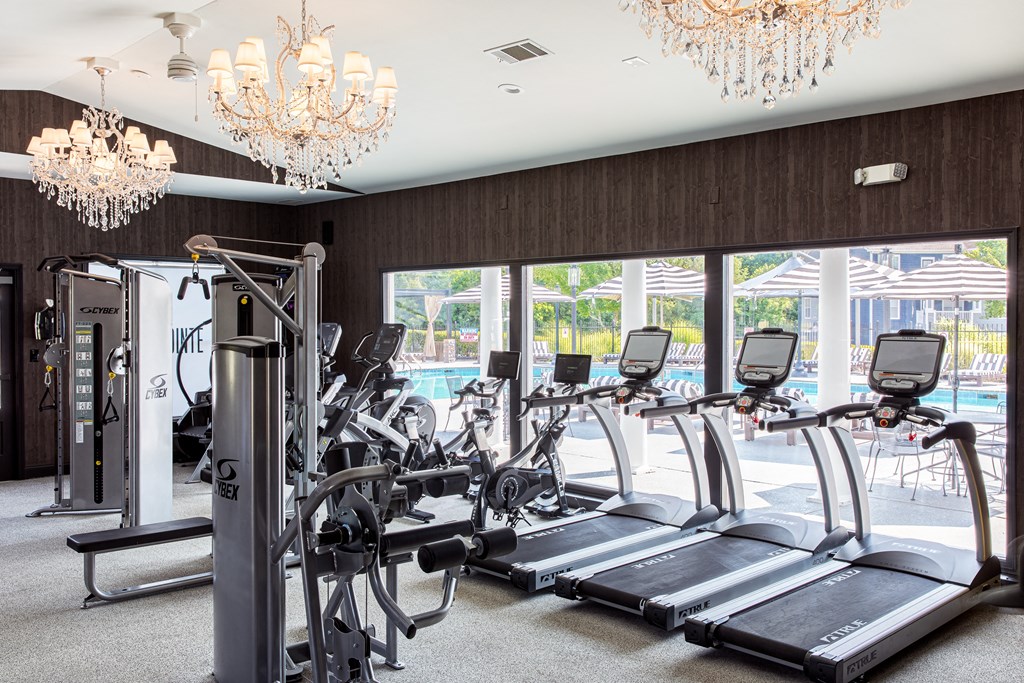 a room with a row of treadmills and two chandeliers hanging from the ceiling