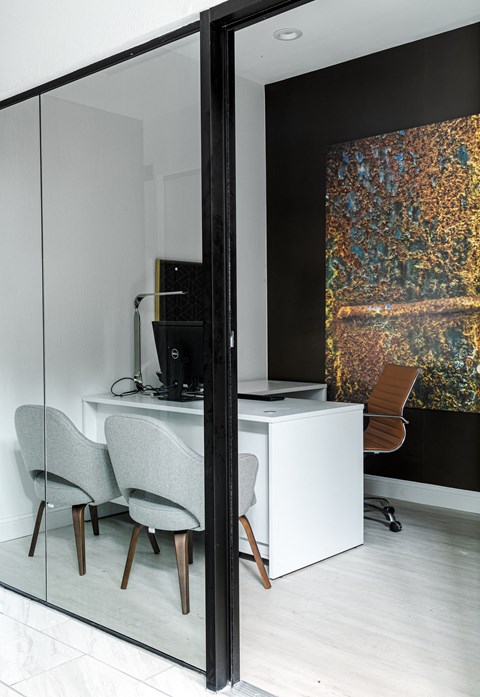 a room with a desk and two chairs and a large painting on the wall
