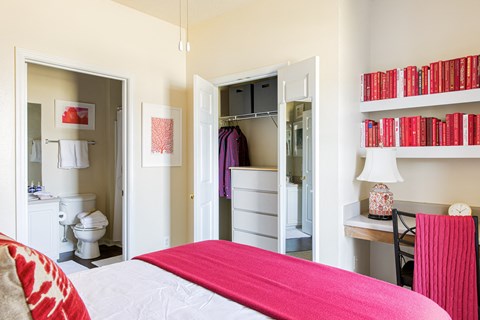 a bedroom with a bed and a bathroom in the background