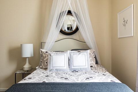 a bedroom with a bed with white bedding and a white canopy over it