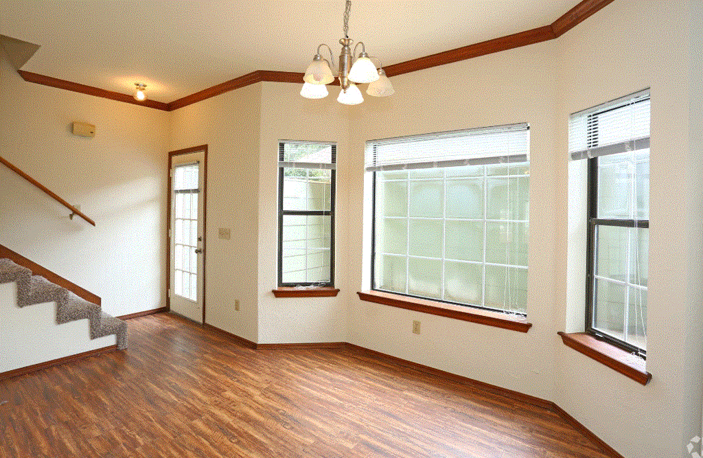 an empty living room with hardwood floors and a chandelier