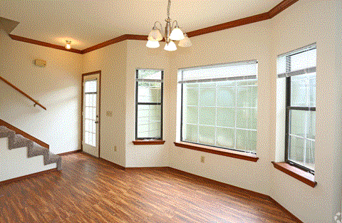 an empty living room with a hard wood floor and windows