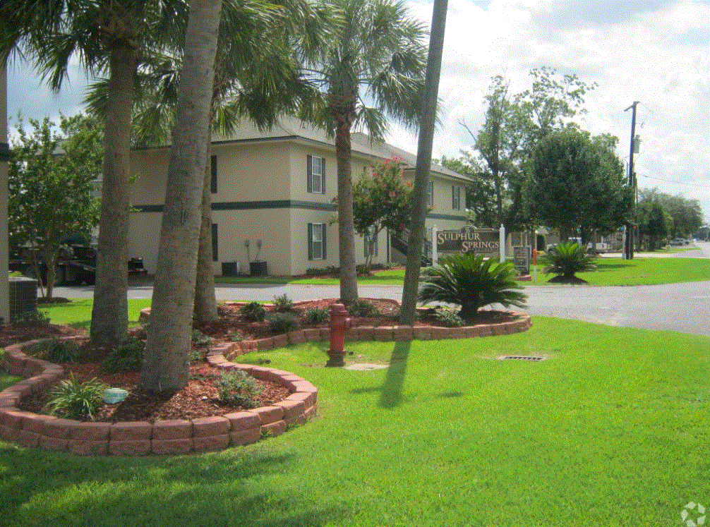 a view of a fire hydrant in a grassy area with a building in the background