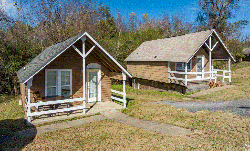 two cottages on a hillside with trees in the background