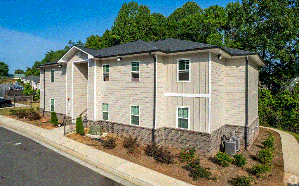 an apartment building with tan siding and a gray roof