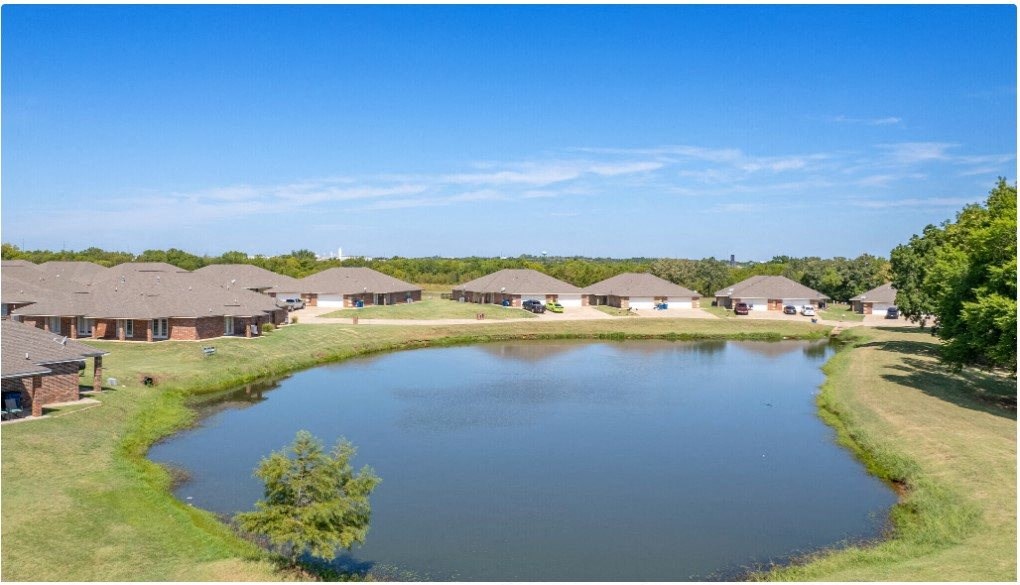 a view of a pond with a row of houses in the background