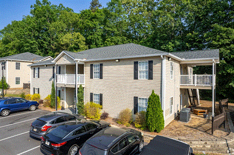 an aerial view of an apartment building with cars parked in a parking lot