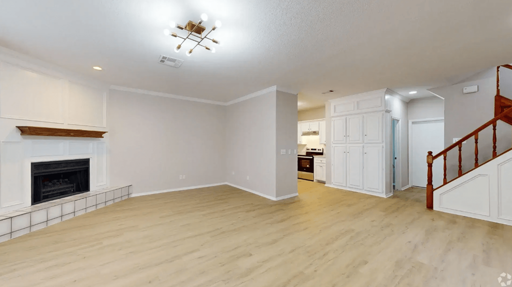 an empty living room with a fireplace and a staircase