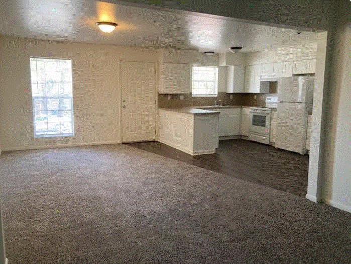 an empty kitchen and living room with a carpeted floor