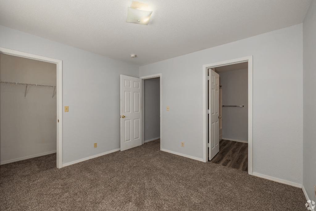 a bedroom with two doors and a carpeted floor