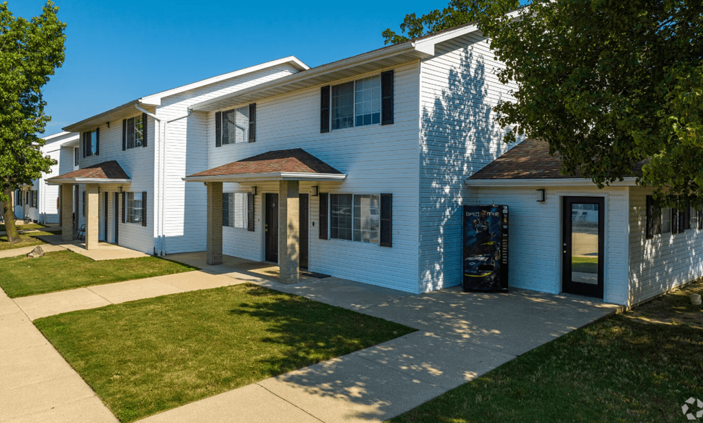 a white building with blue siding and a sidewalk in front of it