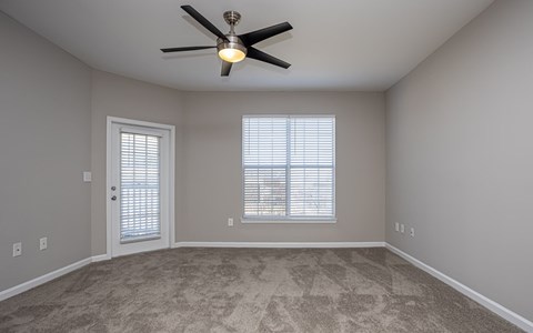 A room with a ceiling fan and two windows.