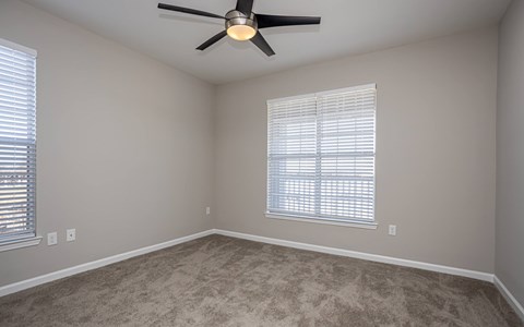 A room with a ceiling fan and a window with blinds.
