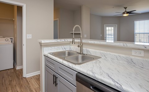 A kitchen with a marble countertop and a stainless steel sink.
