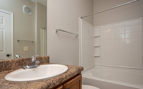 A bathroom with a sink, mirror, and bathtub.