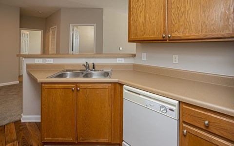 A kitchen with wooden cabinets and a white dishwasher.