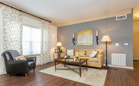A living room with a black leather chair, a wooden coffee table, and a beige sofa.