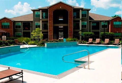 A swimming pool in front of a multi-story apartment building.