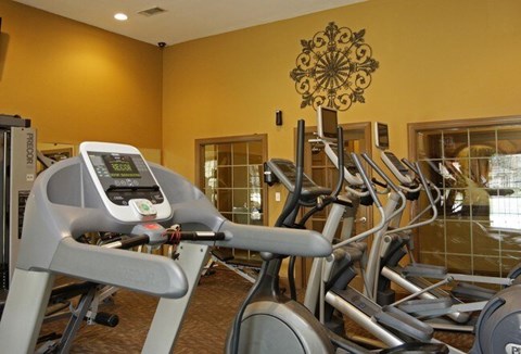 A treadmill with a digital display is in a gym with other treadmills.