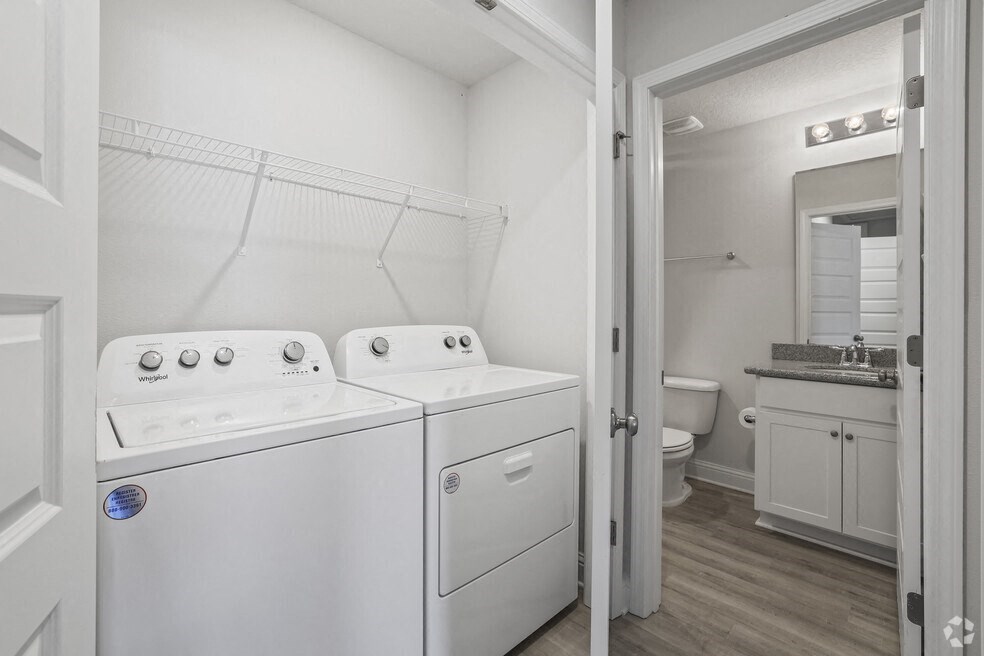 a white laundry room with two white appliances and a bathroom with a toilet