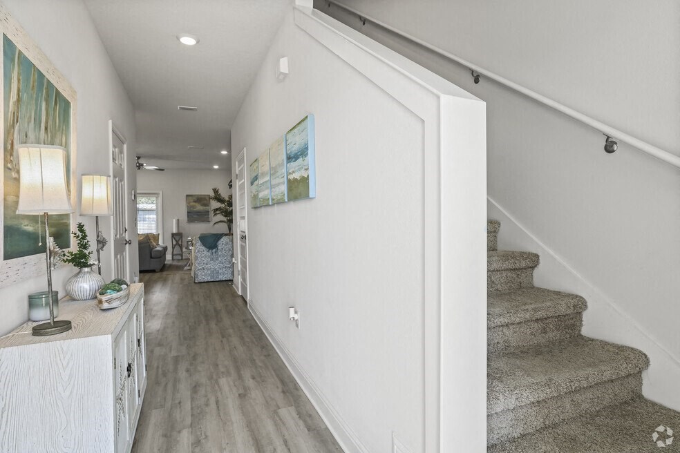 a long hallway with a staircase and a living room with stairs