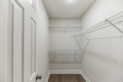 an empty bedroom with white walls and a white closet with metal shelves