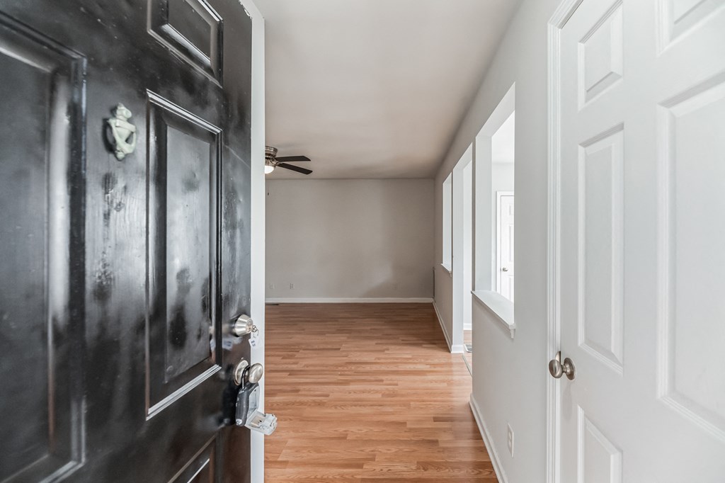 the hallway of a home with a black door and wood floors