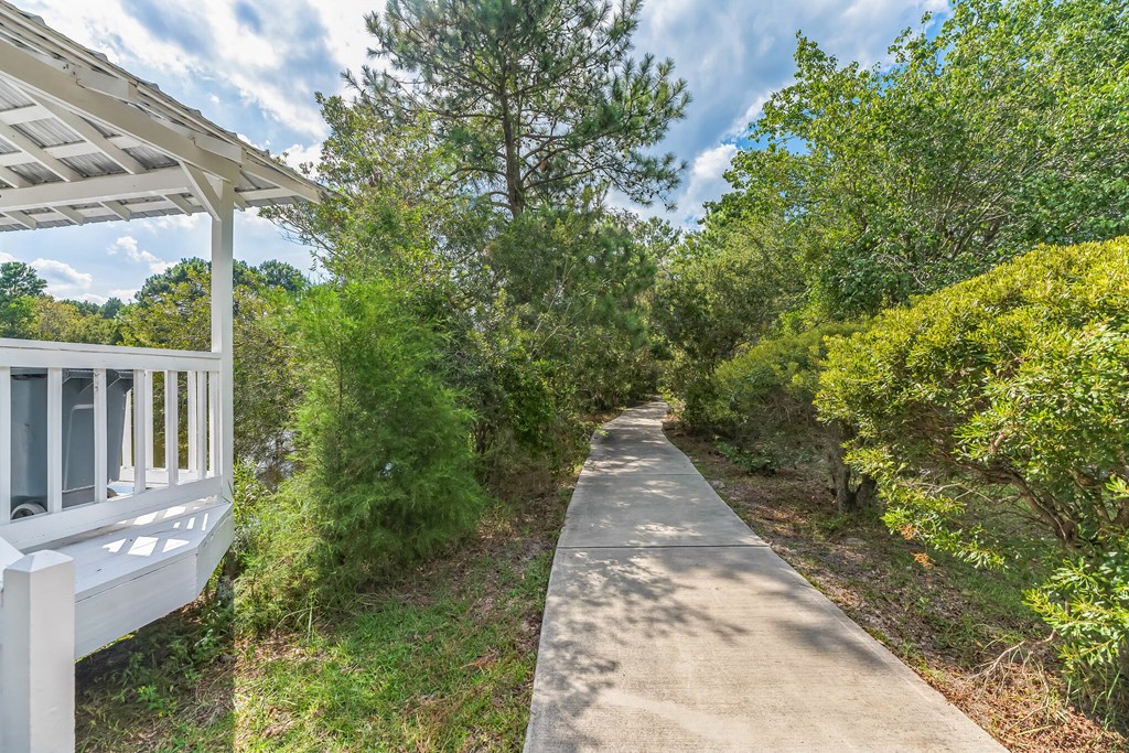 the path to the house is lined with trees and bushes