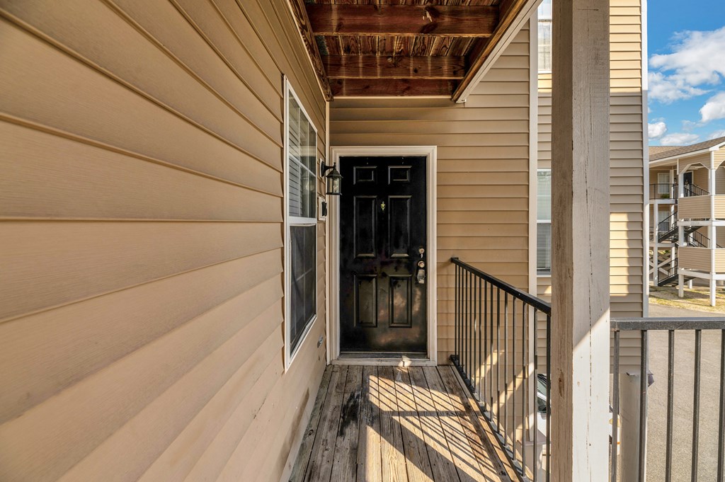 the front porch of a house with a black door