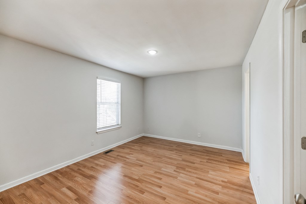 an empty living room with wood flooring and a window