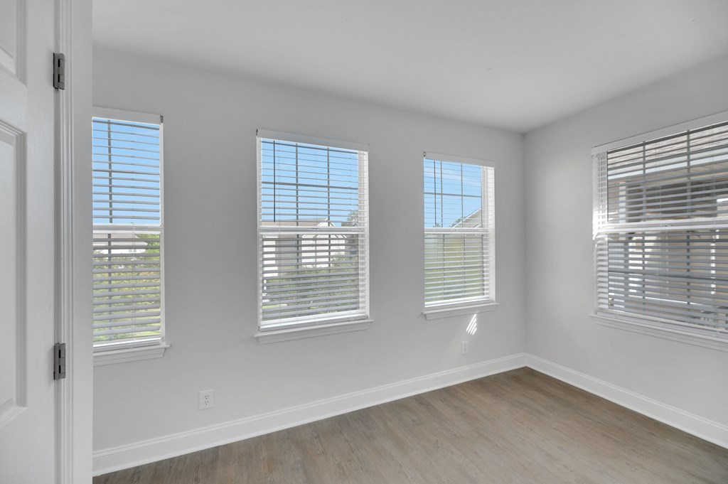 an empty living room with windows and wood floors