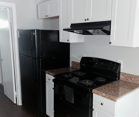 A black stove in a kitchen with white cabinets.