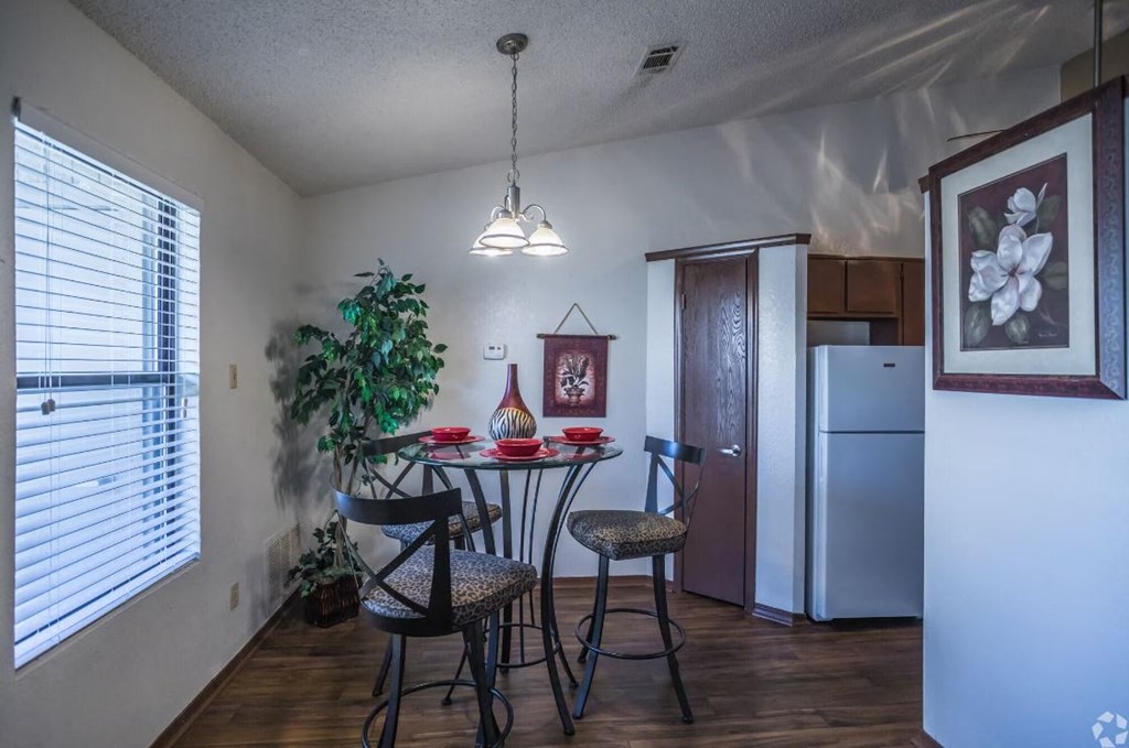 a dining area with a table and chairs and a refrigerator in the corner