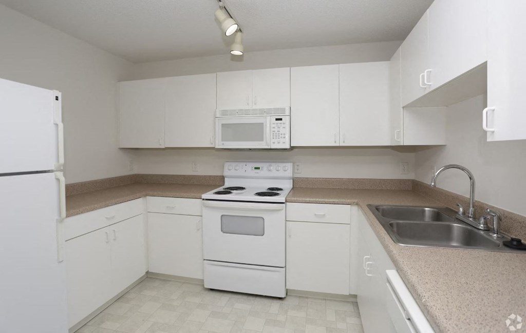 a kitchen with white cabinets and a white stove top oven