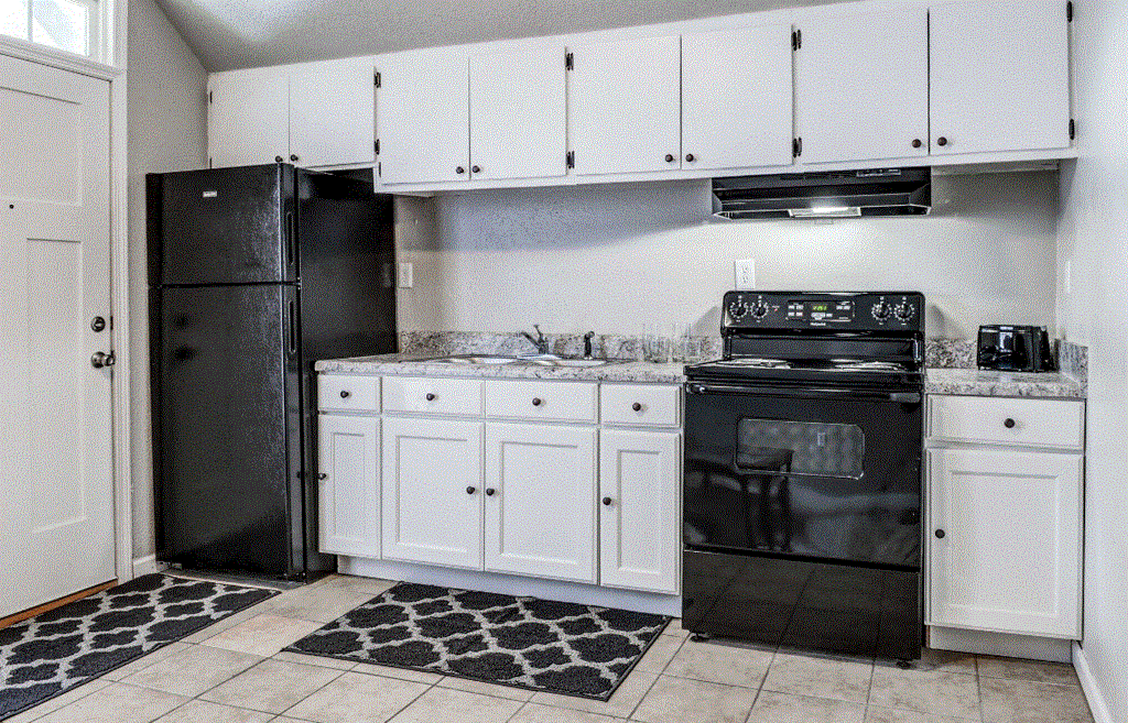 a kitchen with white cabinets and black appliances